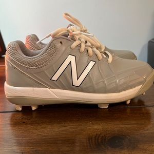 A pair of gray and white New Balance baseball cleats in good condition.